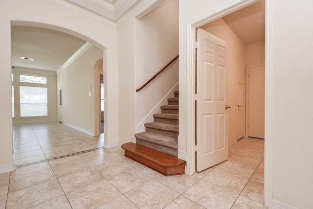 stairs featuring visible vents, ornamental molding, arched walkways, tile patterned flooring, and baseboards