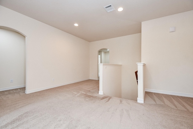 carpeted spare room with recessed lighting, arched walkways, visible vents, and baseboards