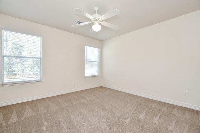 spare room featuring light carpet, plenty of natural light, and baseboards