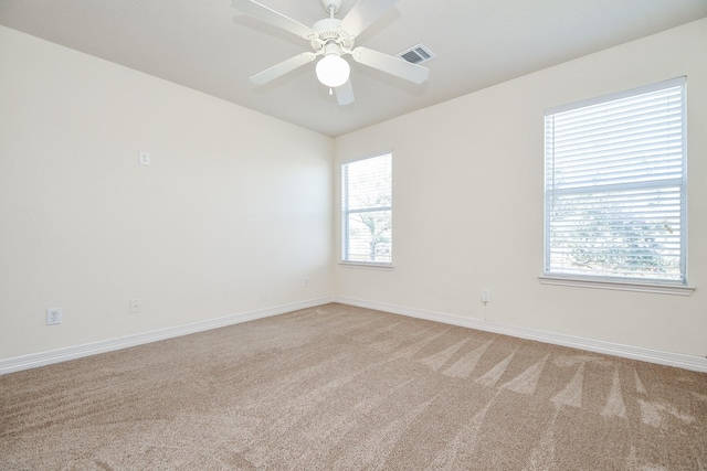 spare room with visible vents, light colored carpet, a ceiling fan, and baseboards