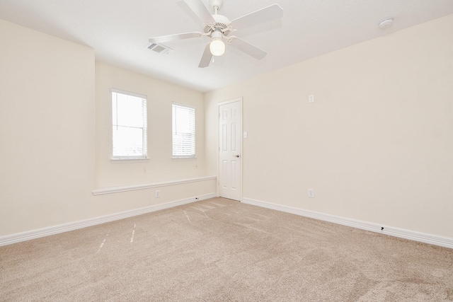 spare room featuring a ceiling fan, light colored carpet, visible vents, and baseboards