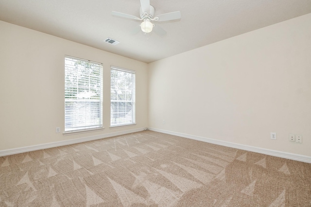 spare room with visible vents, baseboards, light colored carpet, and ceiling fan