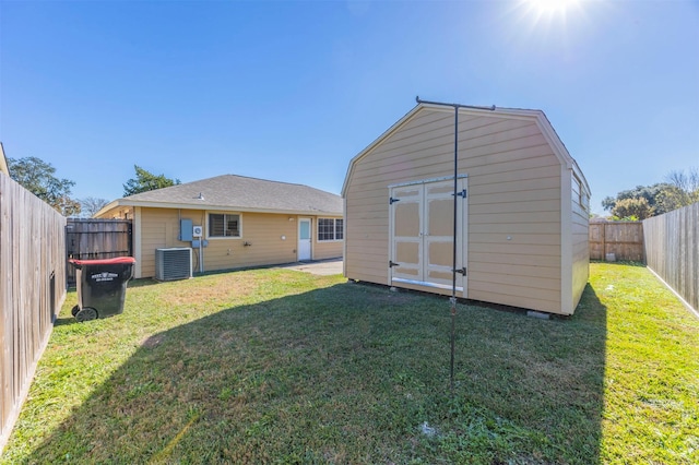 back of house featuring an outdoor structure, a storage unit, central AC unit, and a lawn