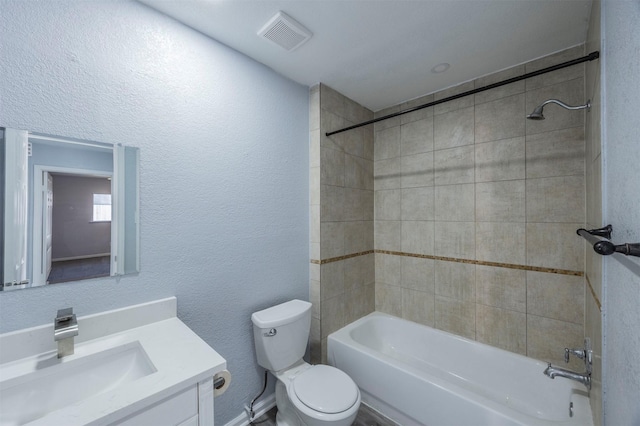 full bathroom with visible vents, toilet, bathtub / shower combination, a textured wall, and vanity