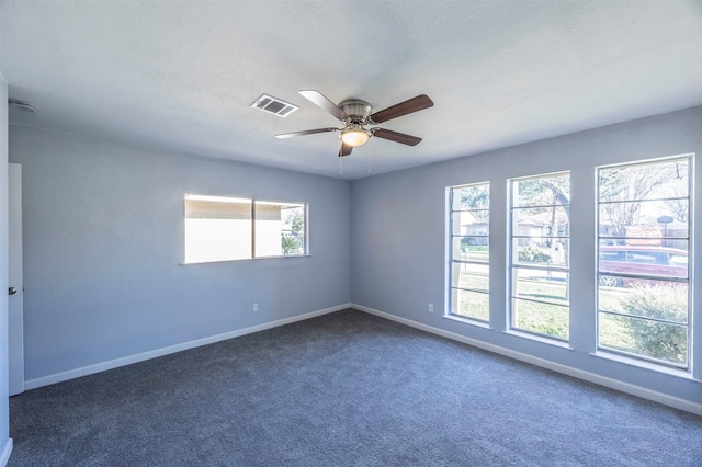 carpeted empty room featuring a ceiling fan, visible vents, and baseboards