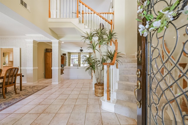 entryway with wallpapered walls, crown molding, stairs, decorative columns, and light tile patterned floors