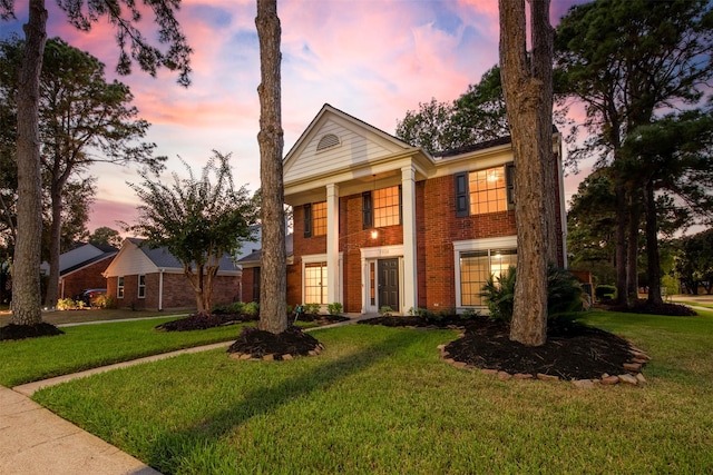 greek revival inspired property featuring a front yard and brick siding