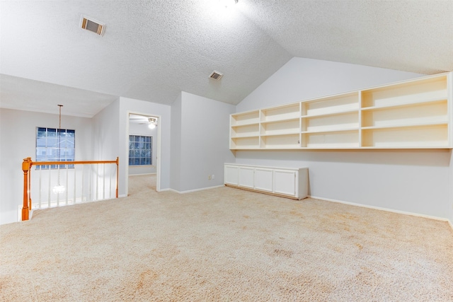 bonus room featuring visible vents, lofted ceiling, carpet, and a textured ceiling