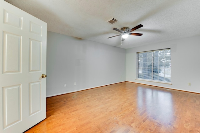 spare room with visible vents, light wood-style floors, a ceiling fan, and a textured ceiling