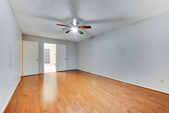 spare room featuring light wood finished floors, visible vents, baseboards, ceiling fan, and a textured ceiling