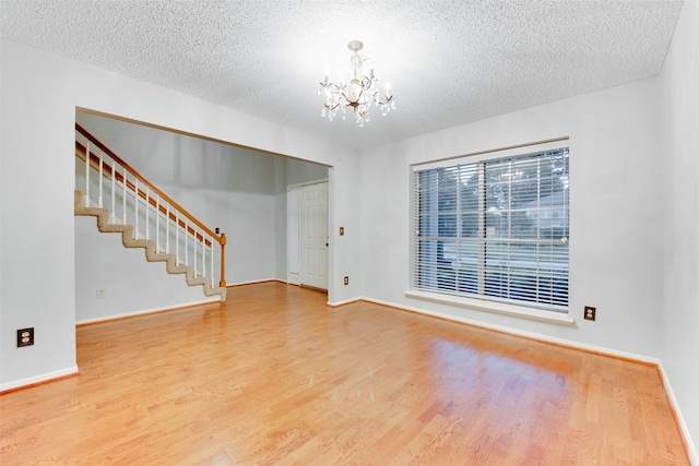 unfurnished room with stairs, wood finished floors, baseboards, and a chandelier