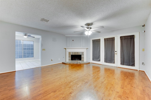 unfurnished living room featuring a textured ceiling, wood finished floors, visible vents, and ceiling fan