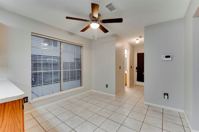 empty room with light tile patterned floors, visible vents, baseboards, and ceiling fan