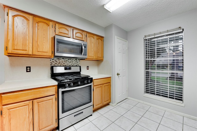 kitchen with tasteful backsplash, light countertops, light tile patterned floors, stainless steel appliances, and a textured ceiling