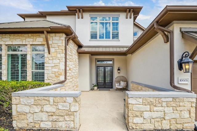 doorway to property featuring french doors, stone siding, and stucco siding