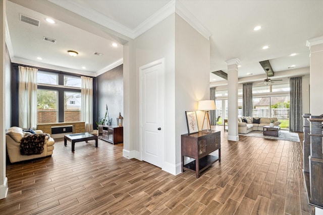 living room with wood finish floors, visible vents, ornamental molding, a ceiling fan, and ornate columns