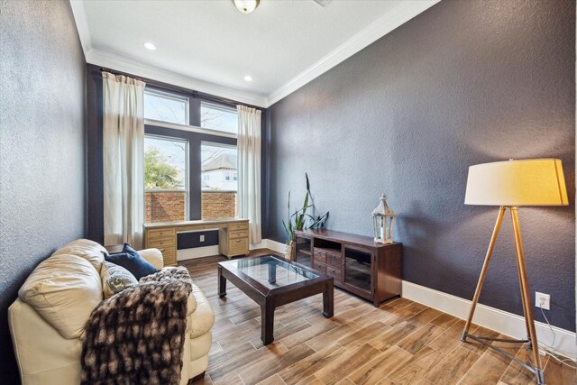 living area featuring baseboards, wood finished floors, a textured wall, and ornamental molding