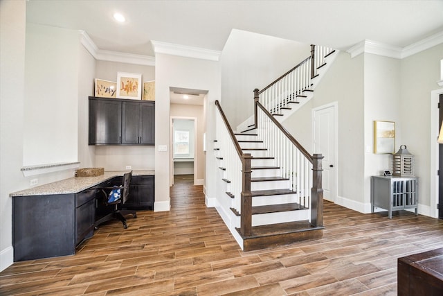 staircase with baseboards, ornamental molding, recessed lighting, wood finished floors, and built in study area