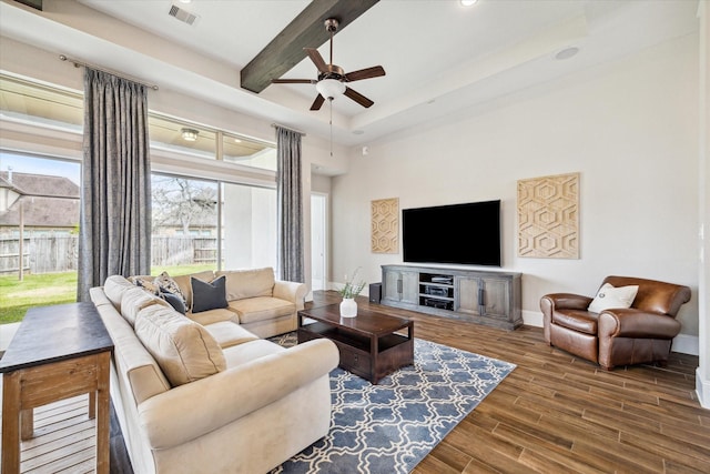 living area with visible vents, baseboards, beamed ceiling, wood finished floors, and a ceiling fan