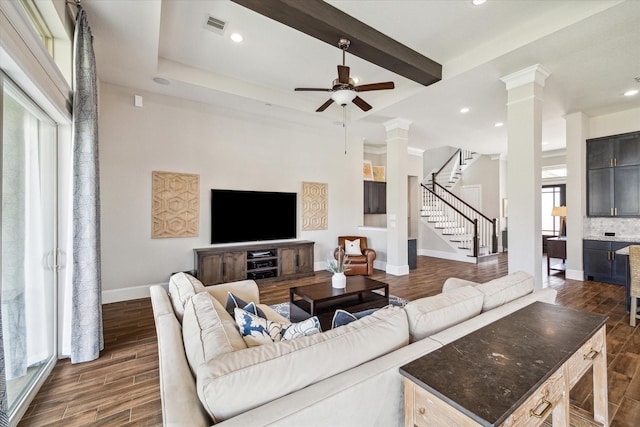 living area with stairway, a ceiling fan, visible vents, ornate columns, and dark wood finished floors