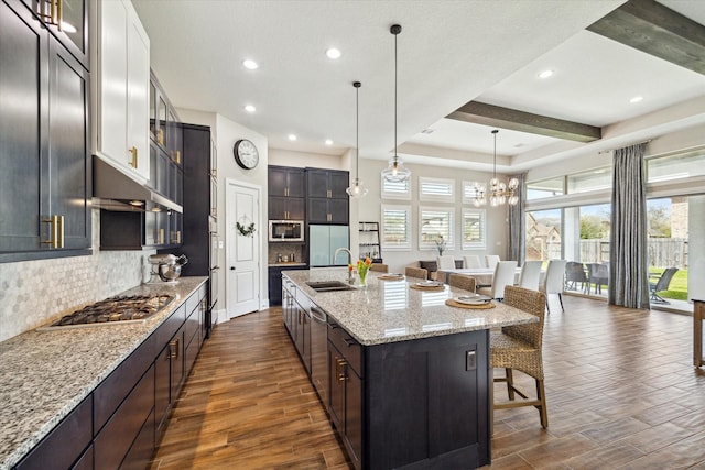 kitchen with a sink, stainless steel appliances, a breakfast bar, and dark wood-style floors