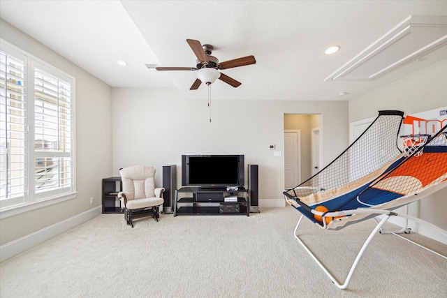 living area with a wealth of natural light, baseboards, attic access, and a ceiling fan