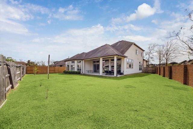 rear view of house with a patio, a lawn, and a fenced backyard