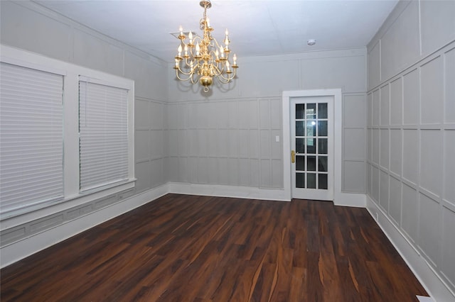 unfurnished dining area with dark wood-type flooring, a notable chandelier, and a decorative wall