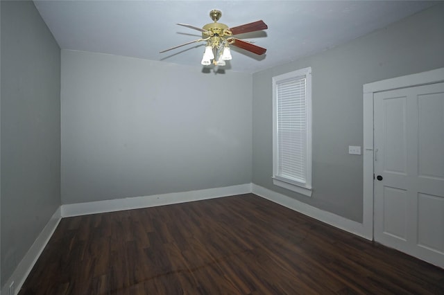 empty room with baseboards, dark wood finished floors, and a ceiling fan