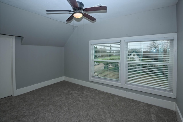 additional living space featuring dark carpet, a ceiling fan, baseboards, and vaulted ceiling