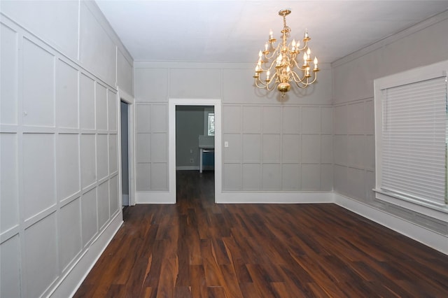 empty room with a notable chandelier, a decorative wall, and dark wood finished floors