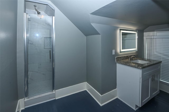 bathroom featuring a shower stall, baseboards, vaulted ceiling, wood finished floors, and vanity