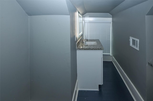 bathroom with visible vents, baseboards, vaulted ceiling, wood finished floors, and vanity