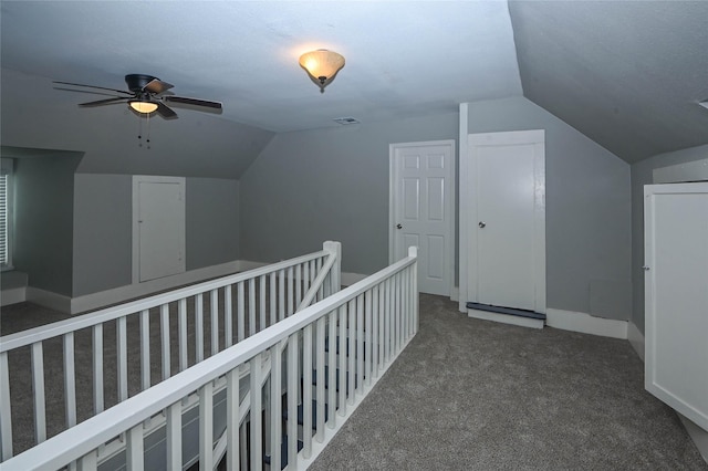 hallway with visible vents, baseboards, lofted ceiling, an upstairs landing, and carpet flooring