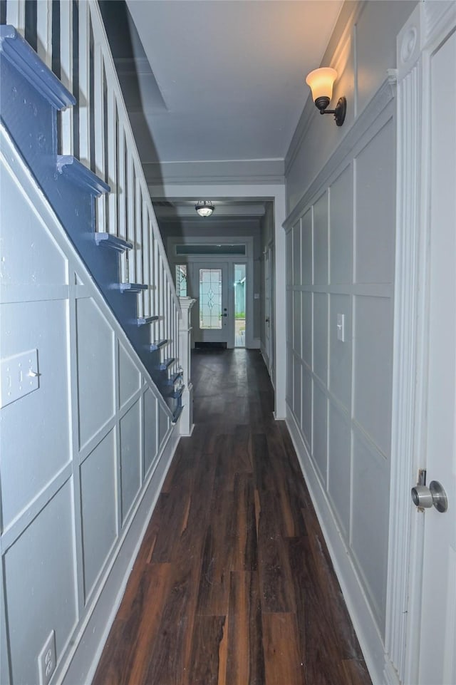 corridor featuring stairs, dark wood-type flooring, and a decorative wall