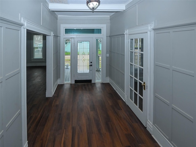 foyer with dark wood finished floors, a decorative wall, and beamed ceiling