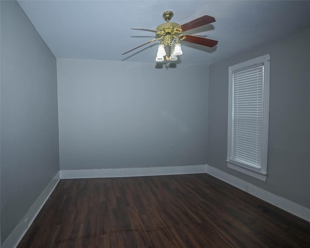 empty room featuring a ceiling fan, baseboards, and dark wood-style flooring