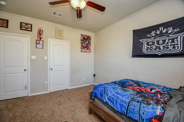 bedroom with a ceiling fan, baseboards, visible vents, ornamental molding, and carpet flooring