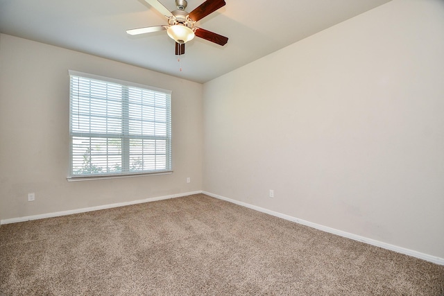 carpeted spare room featuring baseboards and ceiling fan