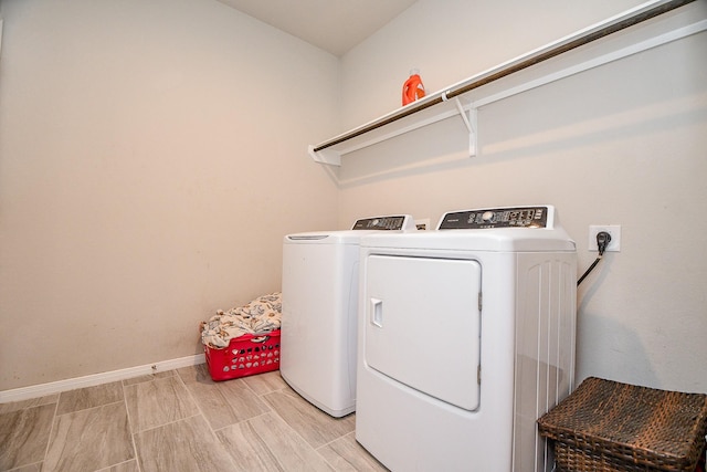 washroom featuring laundry area, washing machine and dryer, baseboards, and wood finish floors