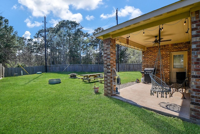 view of yard with a patio area, a ceiling fan, a fenced backyard, and a fire pit