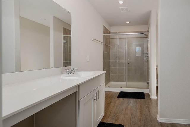 full bath with vanity, visible vents, wood finished floors, and a stall shower