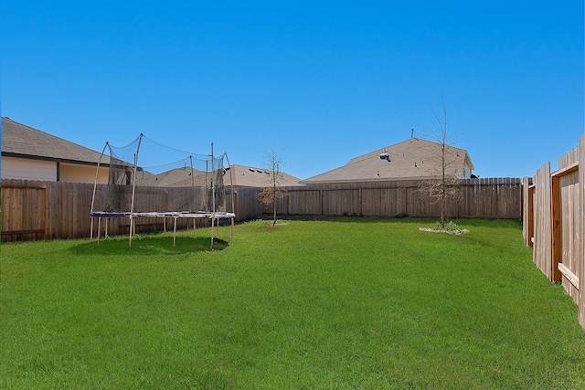 view of yard featuring a trampoline and a fenced backyard