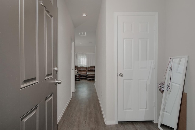 hall featuring visible vents, baseboards, and dark wood finished floors