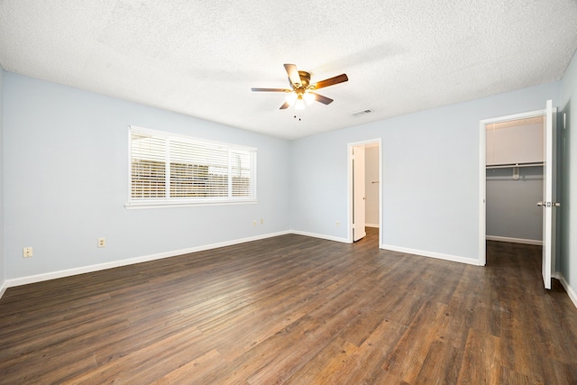 unfurnished bedroom with visible vents, baseboards, dark wood-type flooring, and a spacious closet