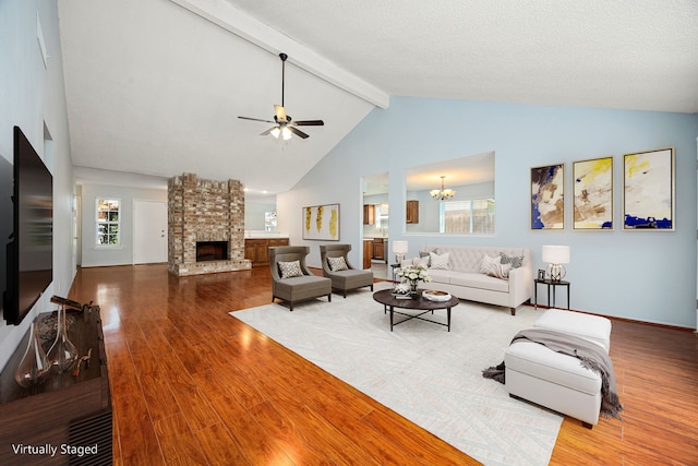 living area featuring a wealth of natural light, beam ceiling, ceiling fan with notable chandelier, and wood finished floors