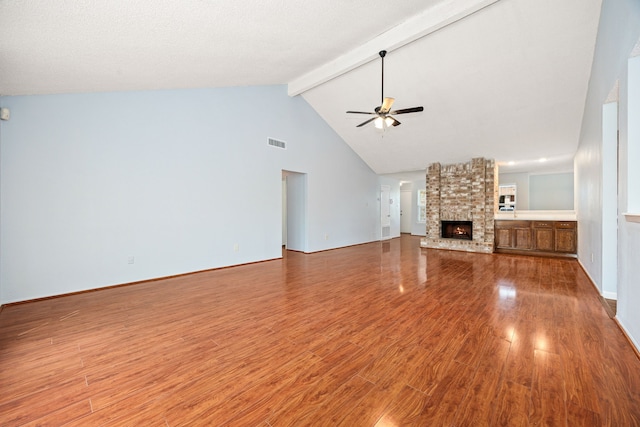 unfurnished living room with visible vents, beam ceiling, wood finished floors, and a ceiling fan