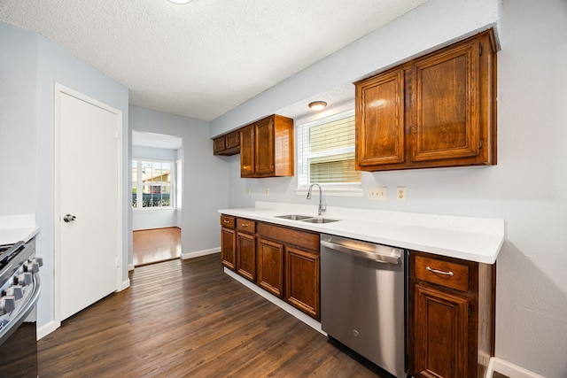 kitchen with light countertops, dark wood-style floors, appliances with stainless steel finishes, and a sink