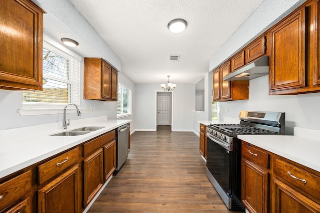 kitchen featuring visible vents, under cabinet range hood, light countertops, stainless steel appliances, and a sink