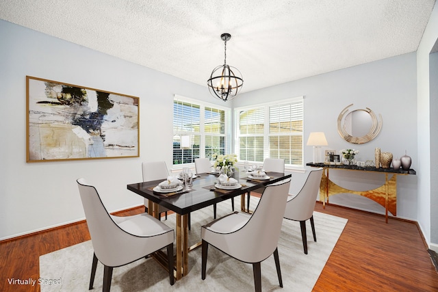 dining room featuring a chandelier, light wood-style flooring, a textured ceiling, and baseboards